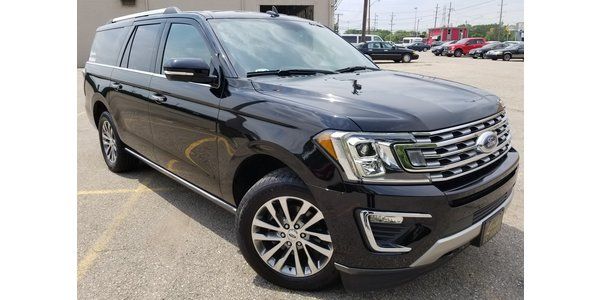 A black ford expedition is parked in a parking lot.
