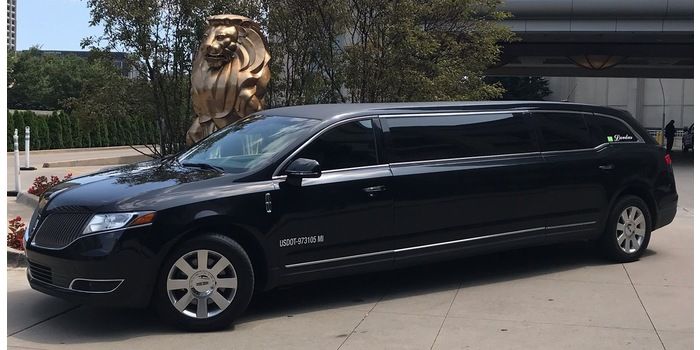 A black limousine is parked in front of a building.