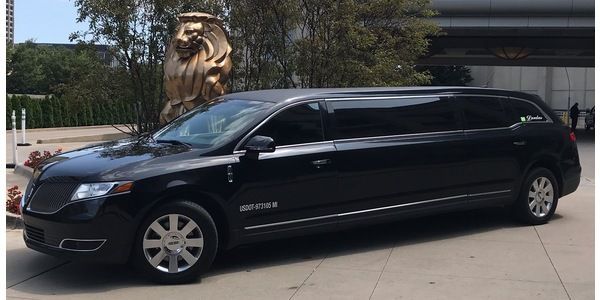 A black limousine is parked in front of a building.