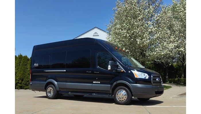 A black van is parked in a parking lot in front of a building.