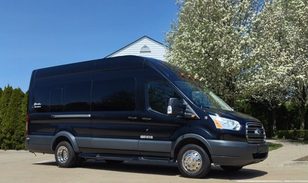 A black van is parked in a parking lot in front of a building.
