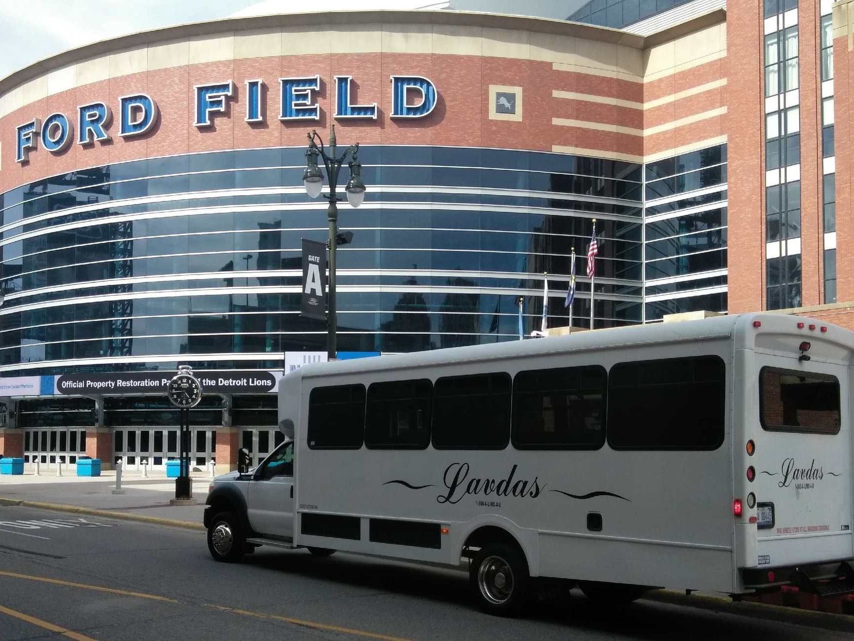 A white bus is parked in front of ford field