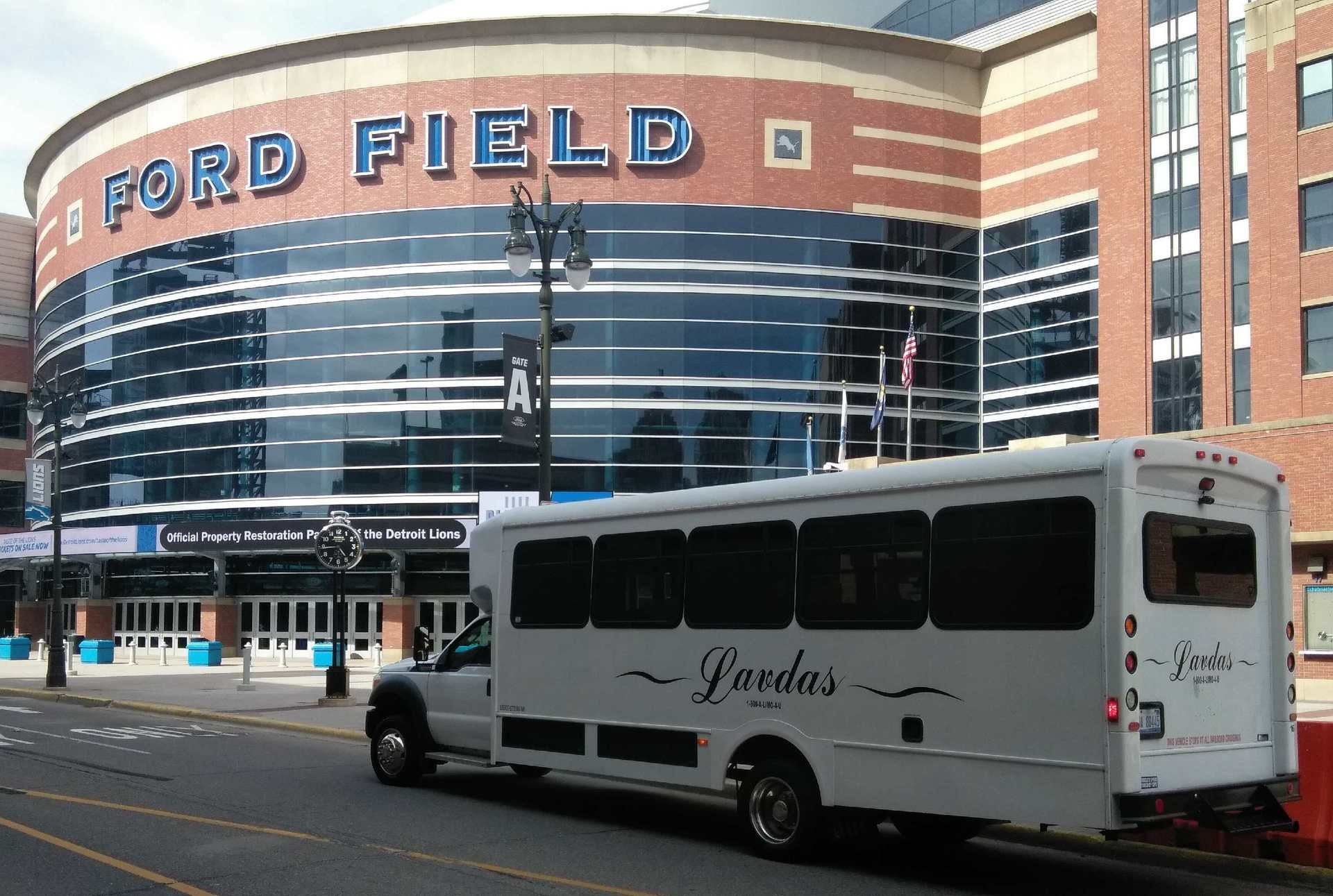 A white bus is parked in front of ford field