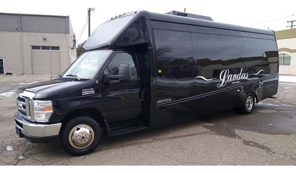 A black shuttle bus is parked in front of a building.