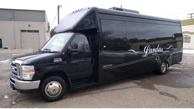 A black shuttle bus is parked in front of a building.