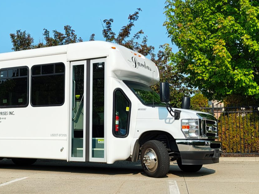 A white bus with the word landa on the front is parked in a parking lot