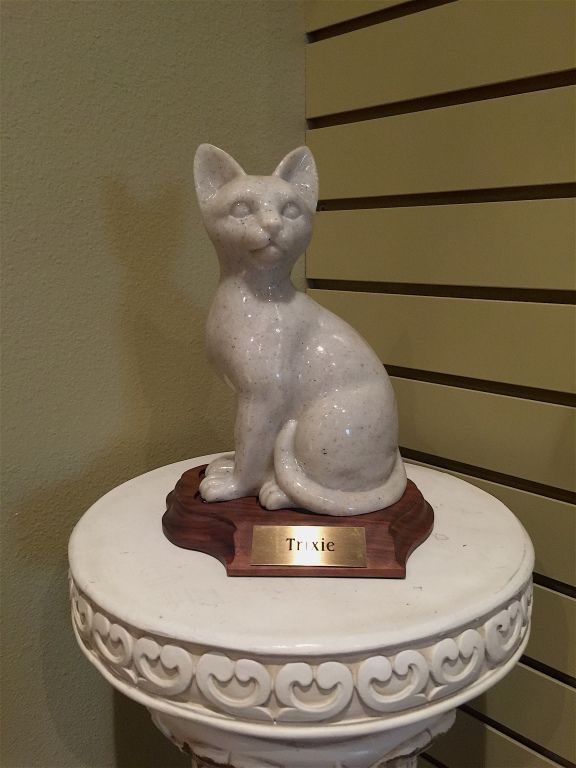 Statue of a white cat on a pedestal, nameplate says 