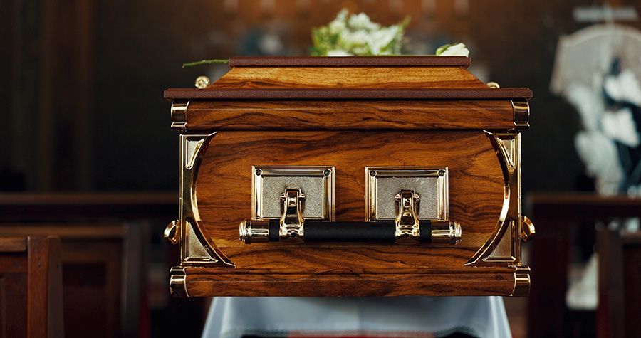 Wooden casket with gold handles on a table in a church.