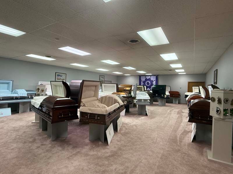 A funeral home showroom displaying various caskets on pedestals; neutral colors.