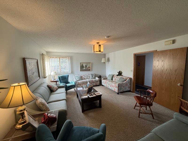 Living room with sofas, chairs, a coffee table, and a doorway; neutral colors.