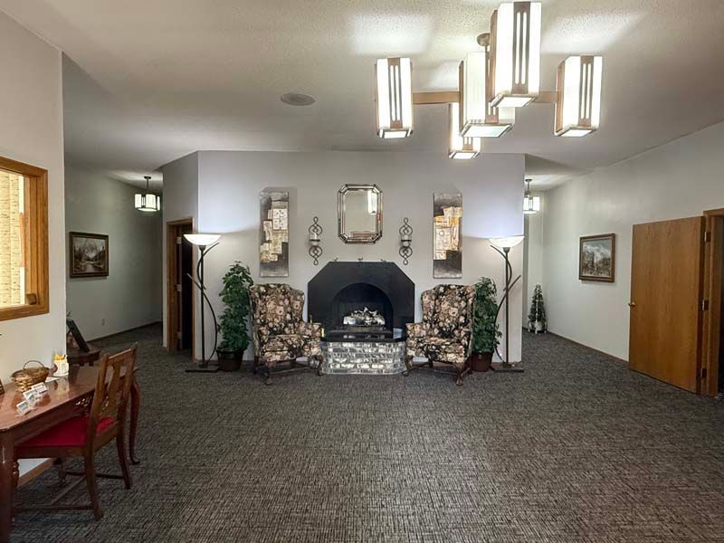 A well-lit waiting room with a fireplace, armchairs, and decorative mirrors.