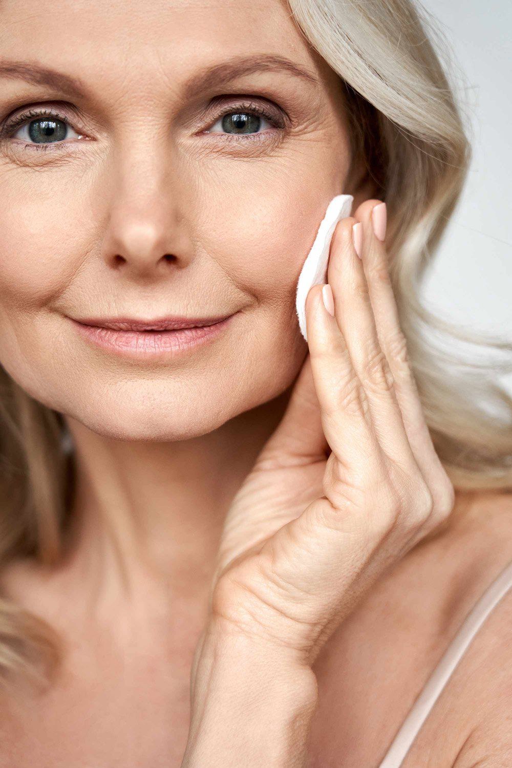 woman wiping her face with a cotton round