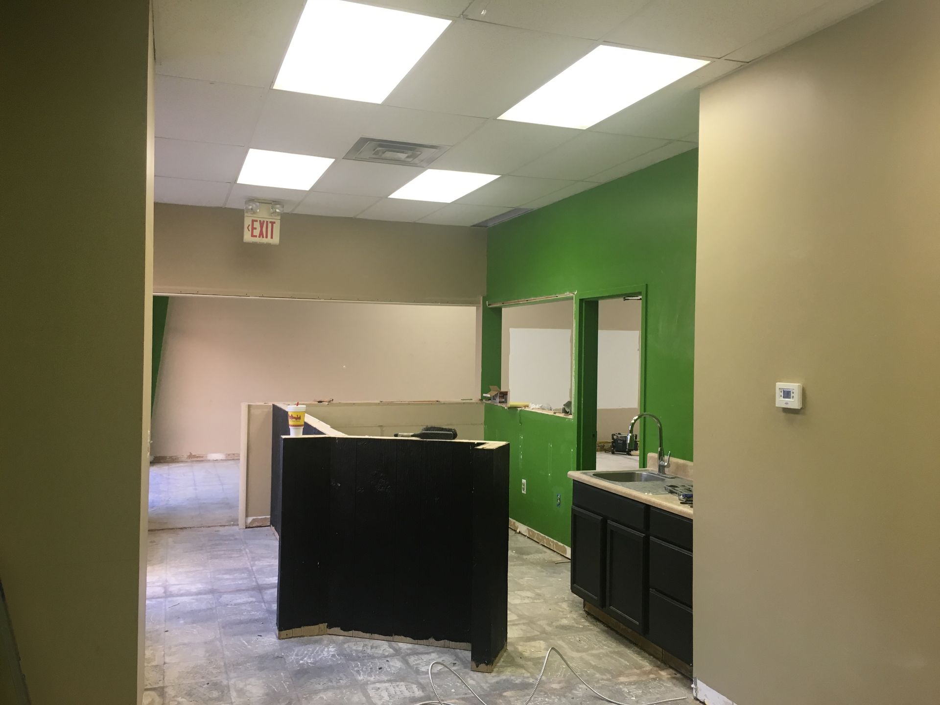 an empty office with green walls and a black counter .