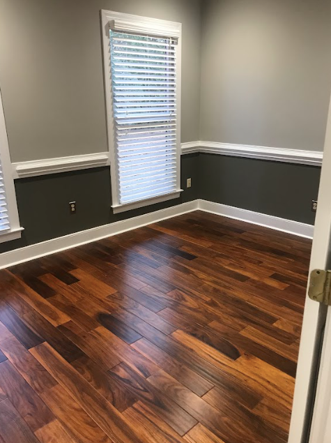 an empty room with hardwood floors and two windows .