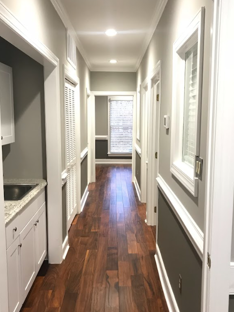 A long hallway with hardwood floors and white cabinets