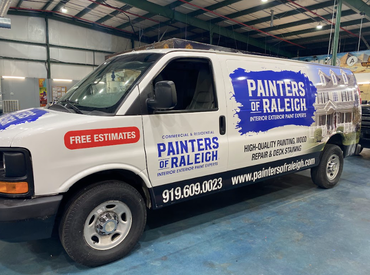 A painters of raleigh van is parked in a garage.