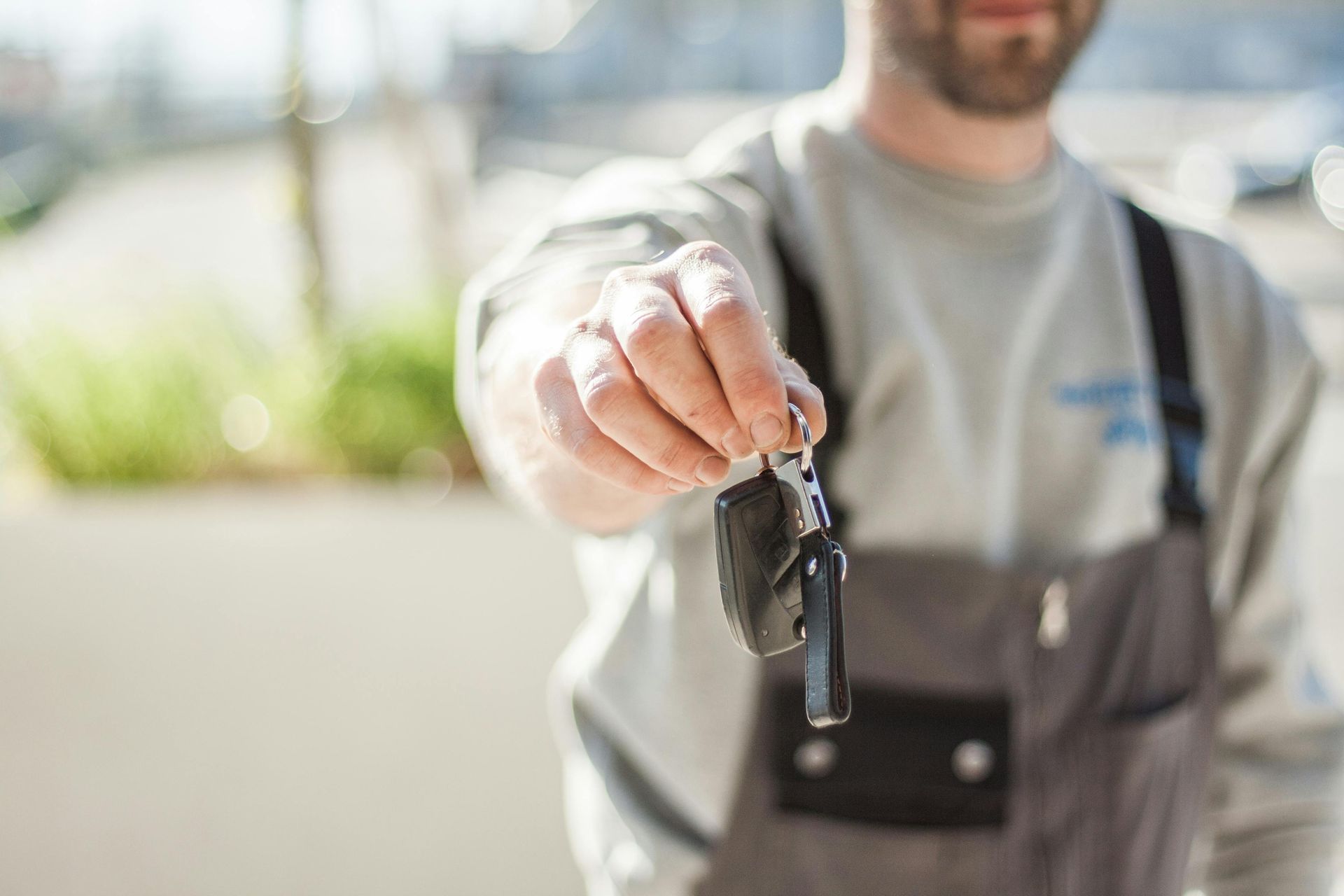 Person in grey jumpsuit holding out car keys.