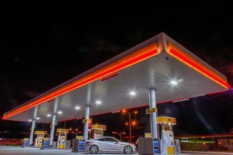 A car is parked under a gas station at night.