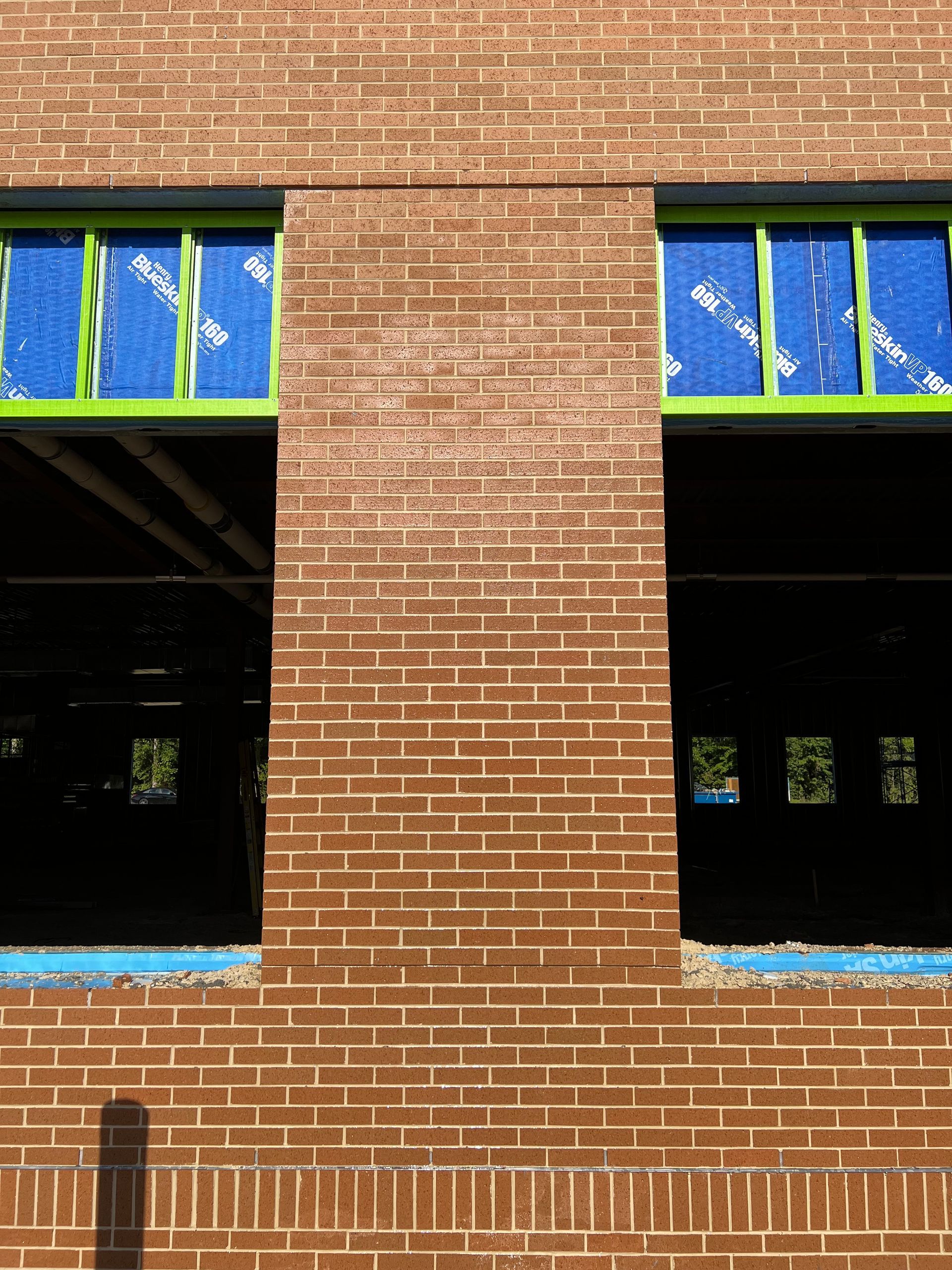 A brick building under construction with green windows