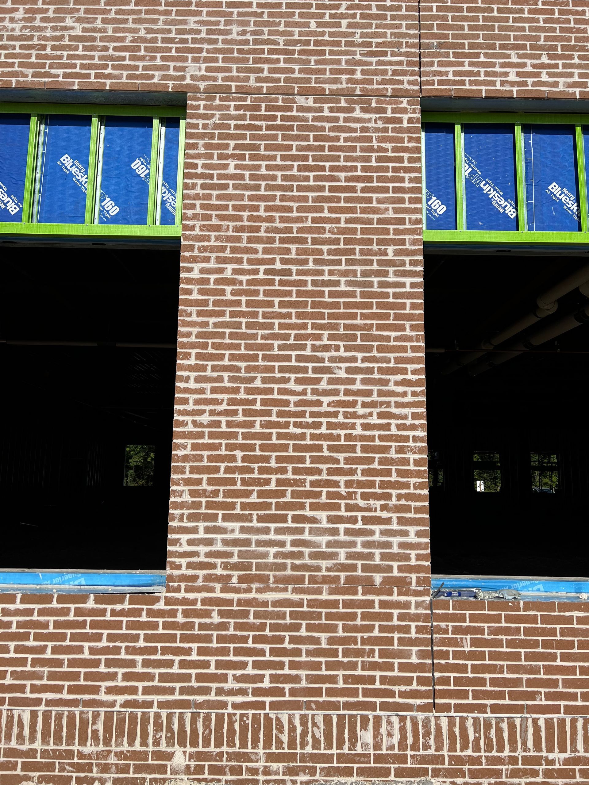 A brick building under construction with green windows