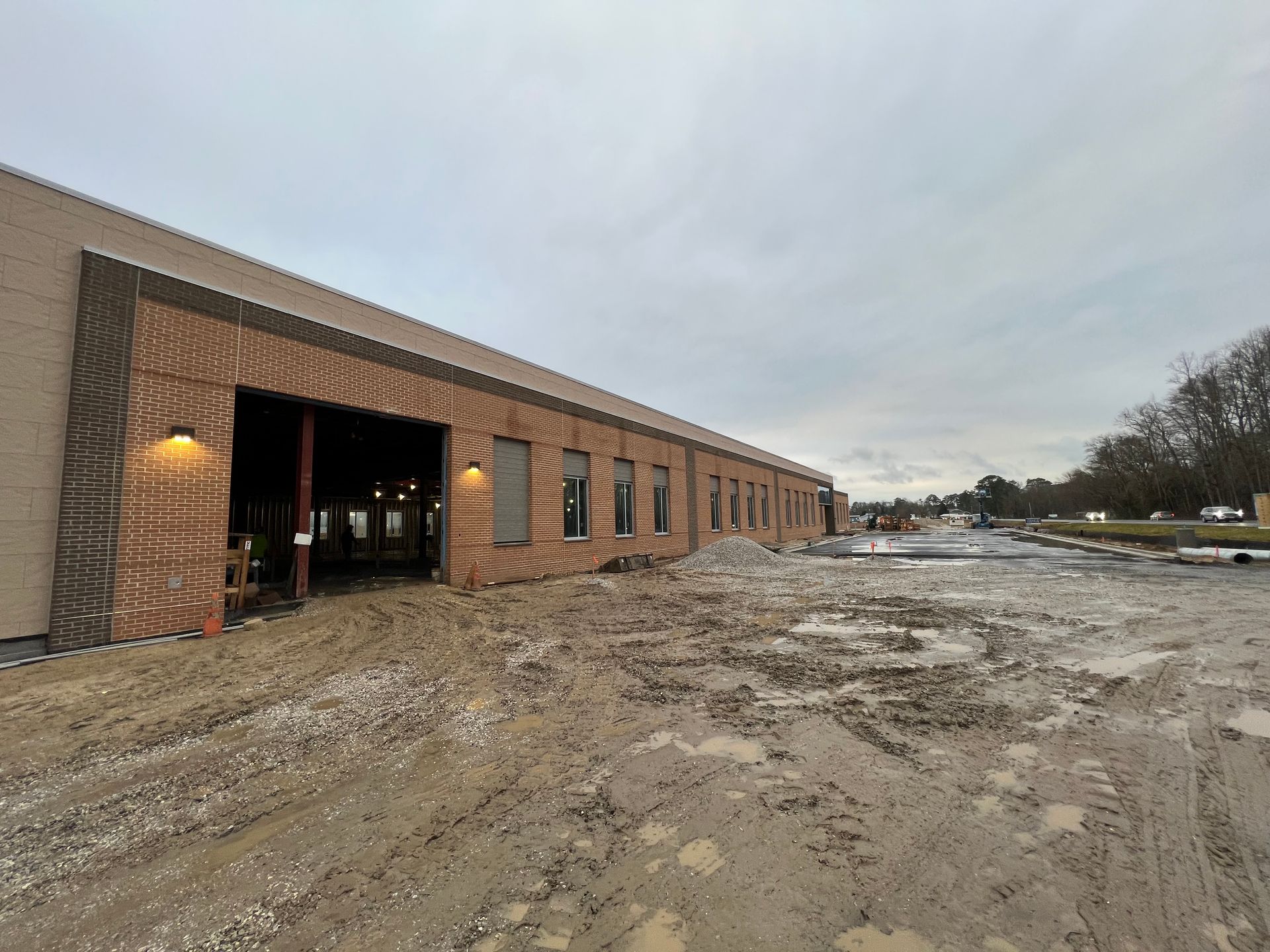 A large brick building is being built next to a dirt road.