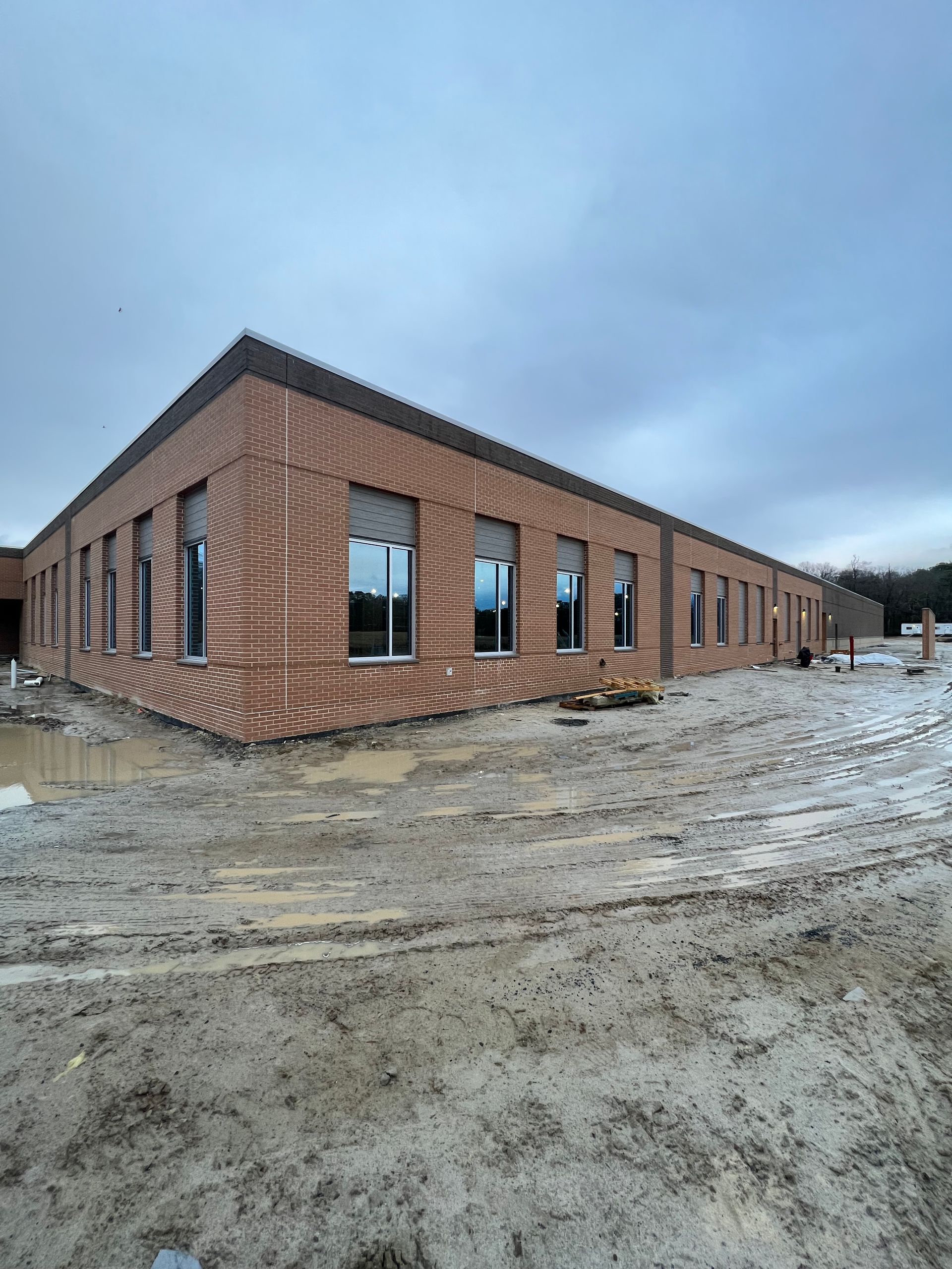 A large brick building is being built in the middle of a dirt field.