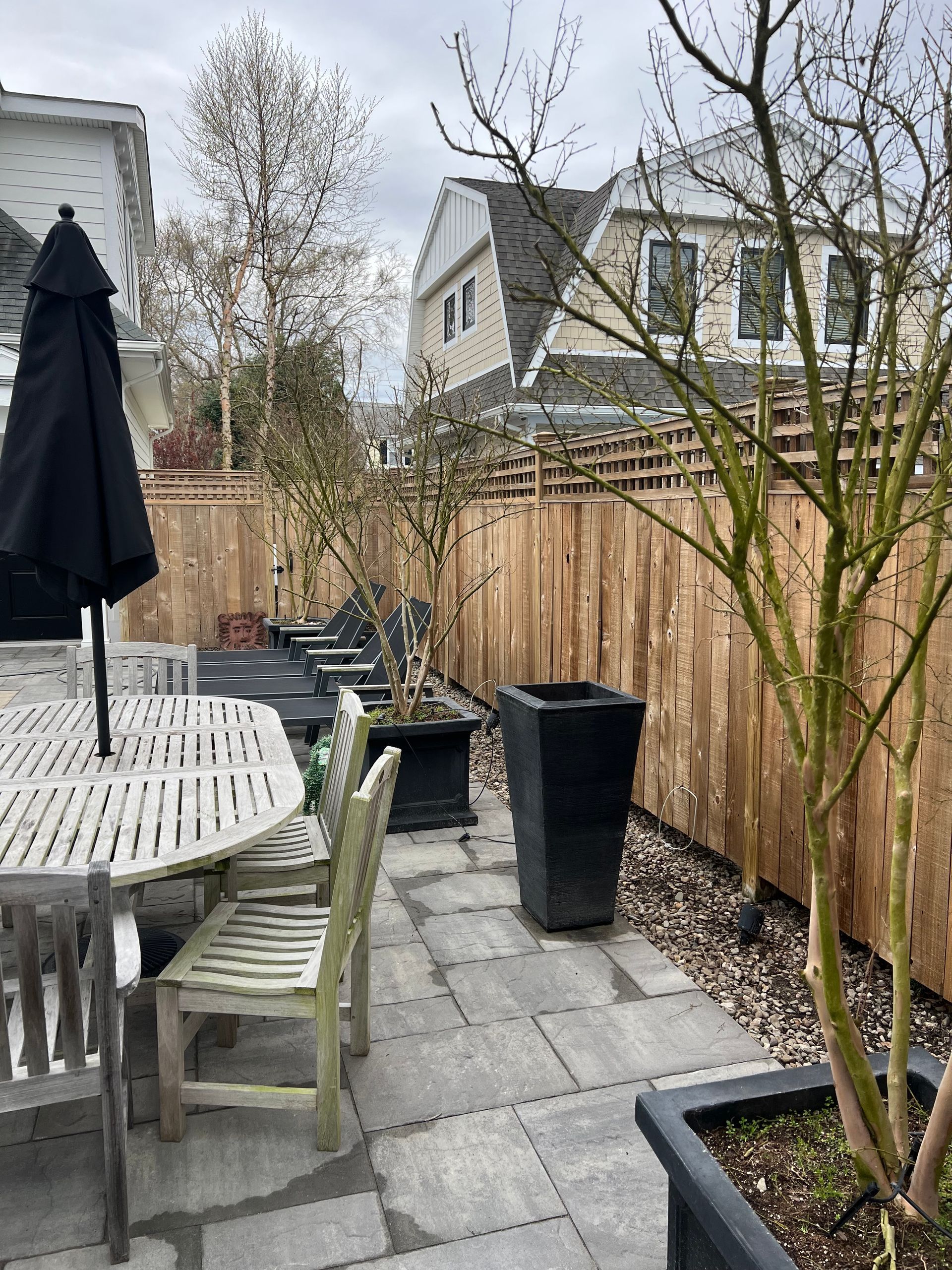 A patio with a table , chairs , umbrella and potted plants.