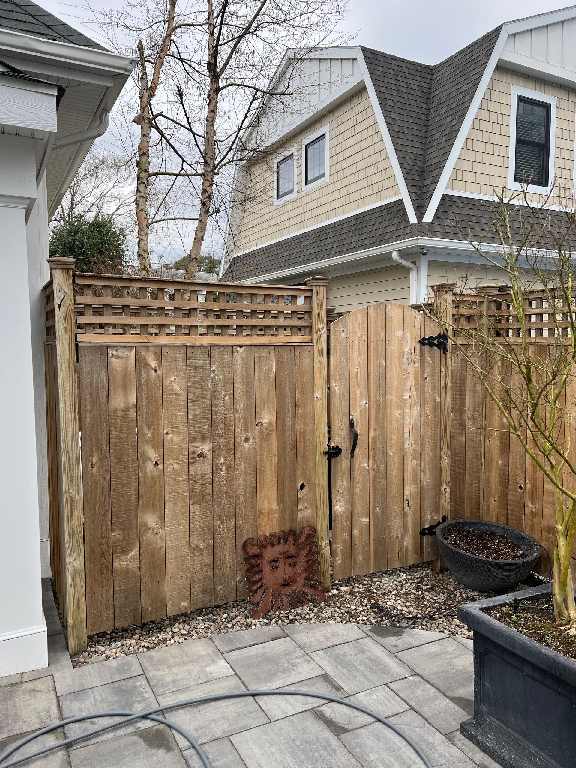 A wooden fence is surrounding a patio in front of a house.