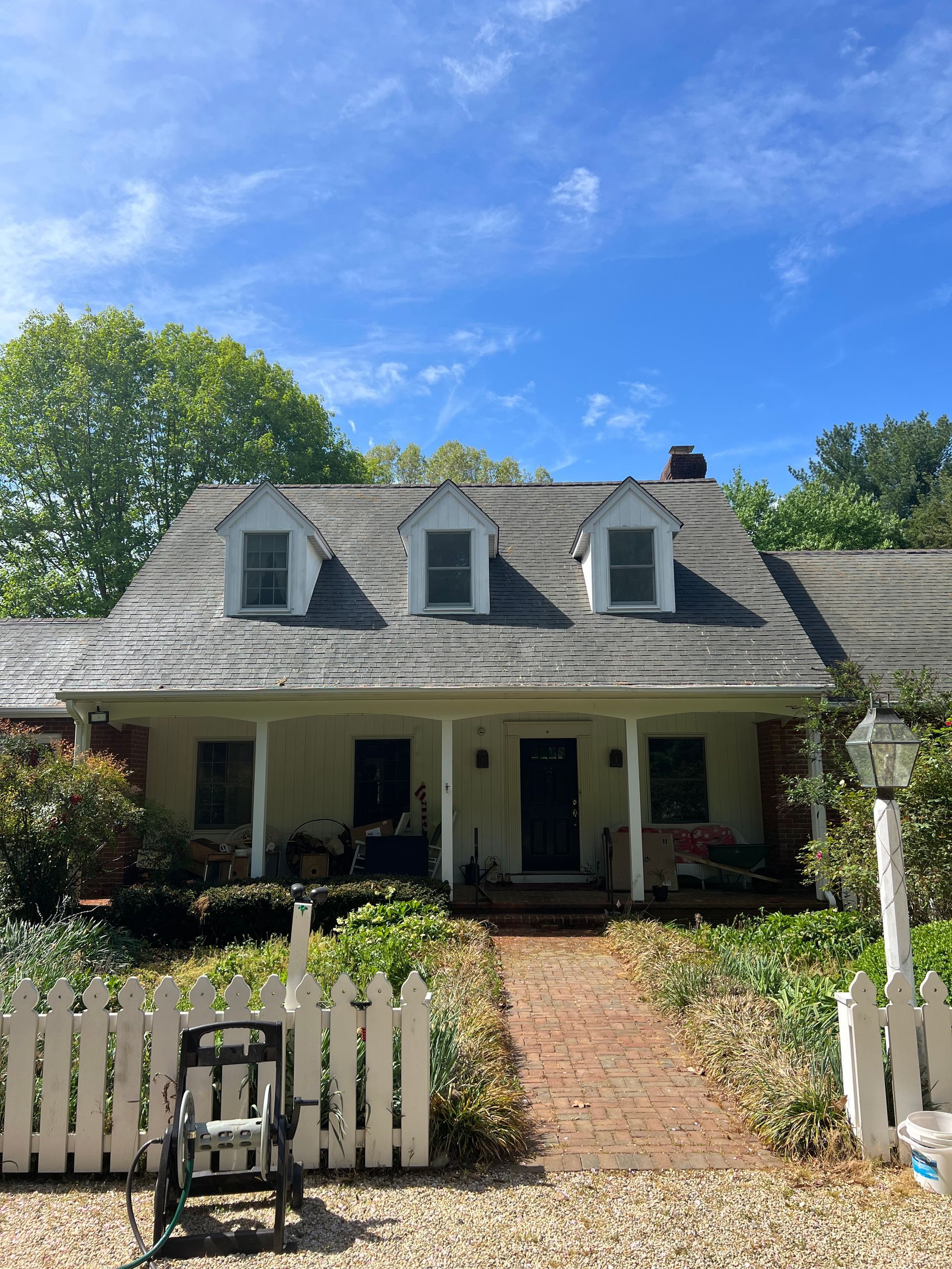 A white house with a slate roof and a white picket fence.