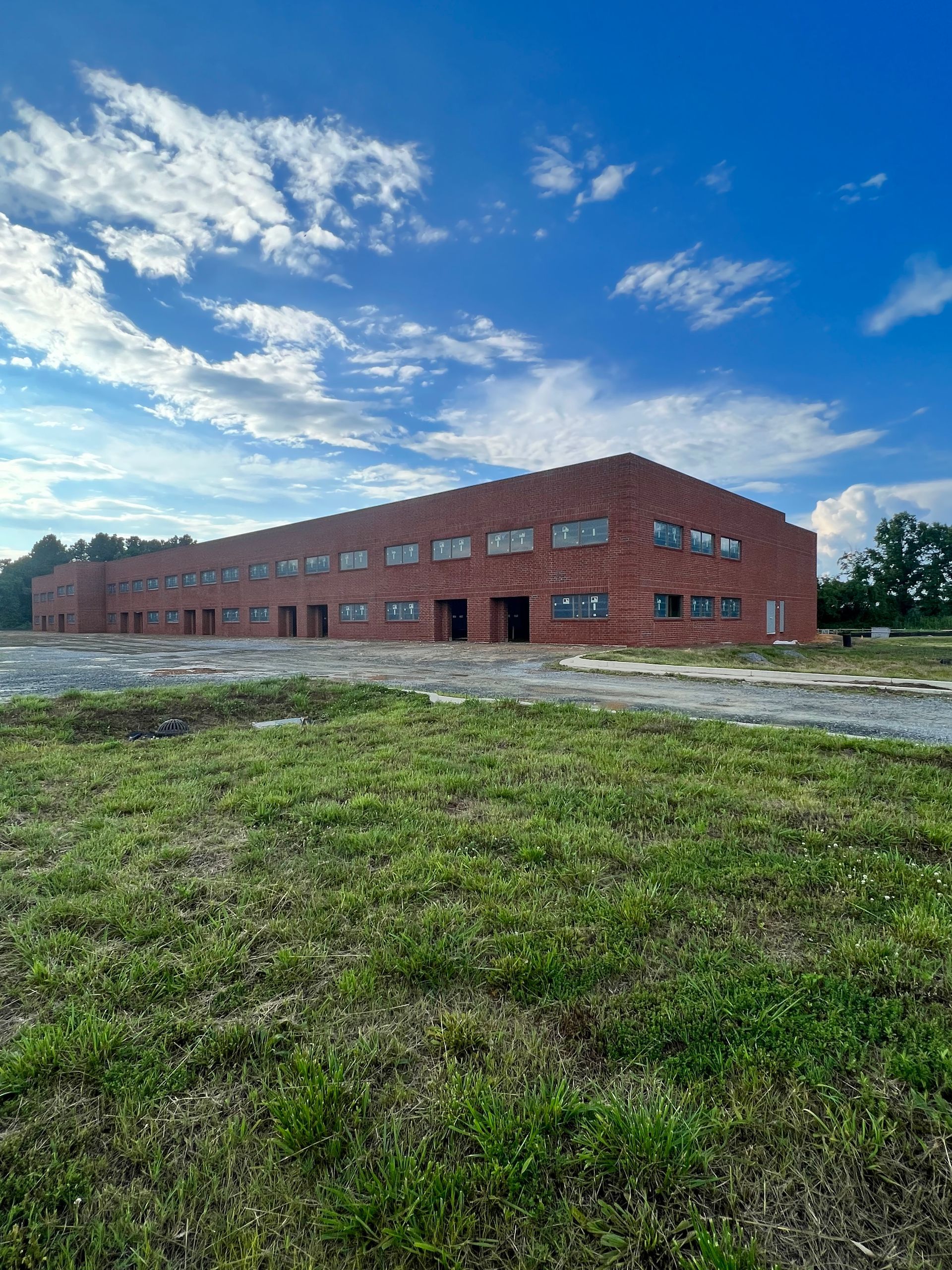 A large brick building is sitting in the middle of a grassy field.