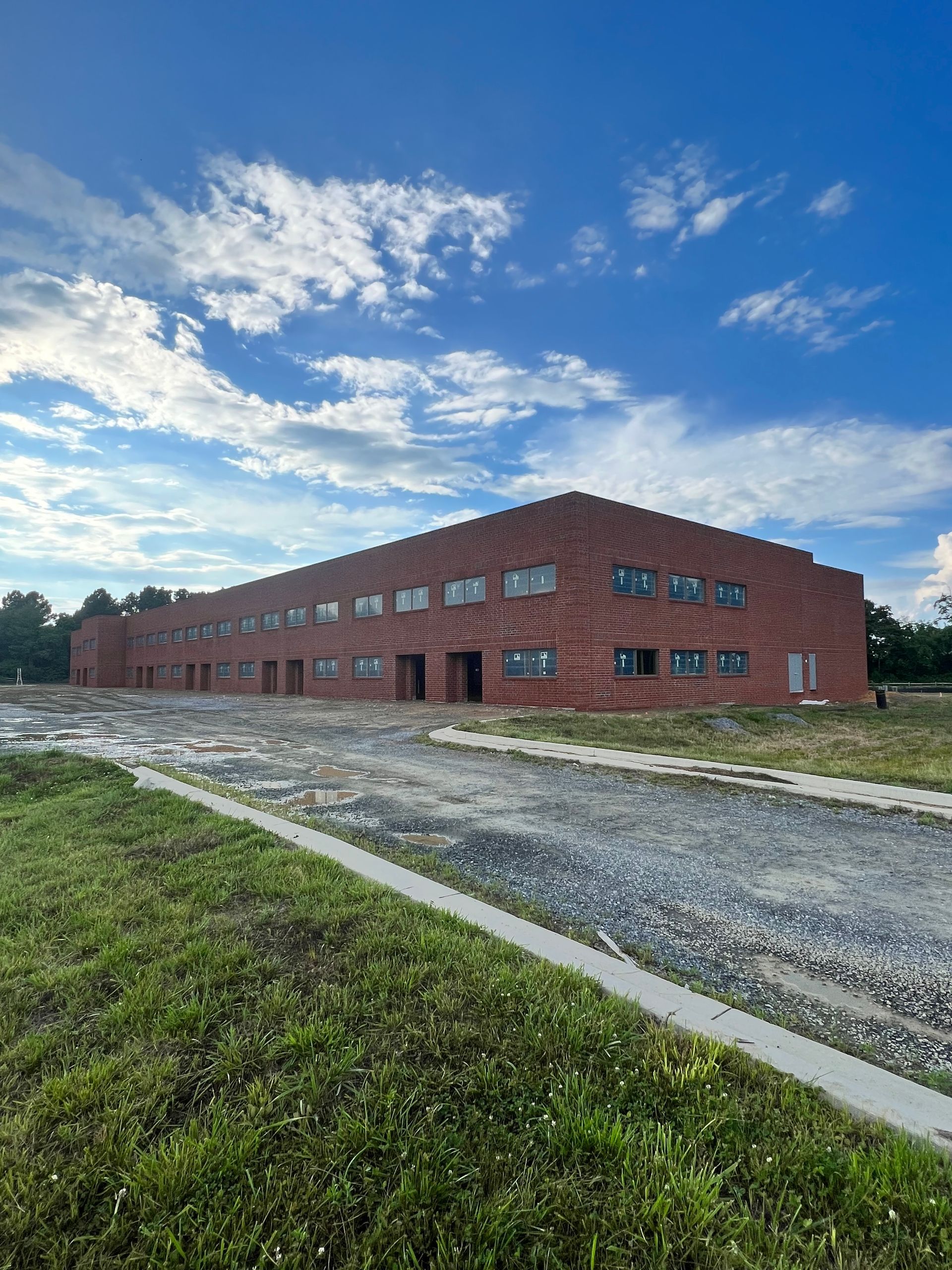 A large brick building is sitting in the middle of a grassy field.