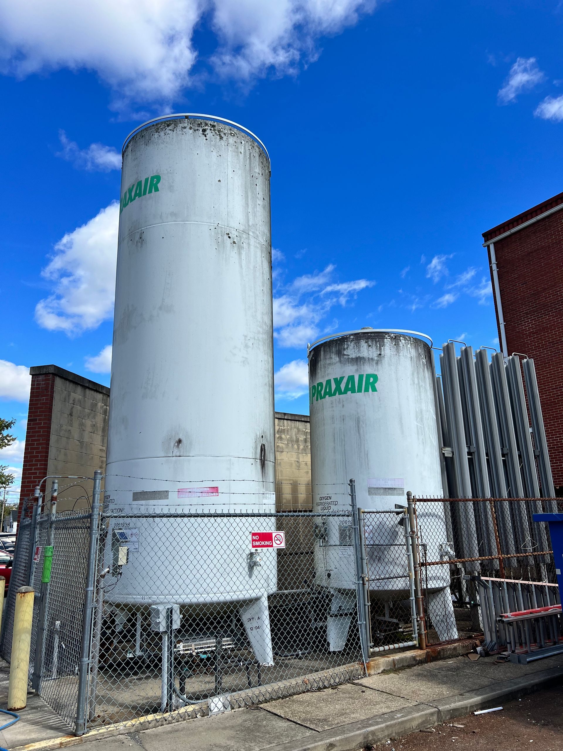 Two large white tanks are sitting next to each other in a fenced in area.
