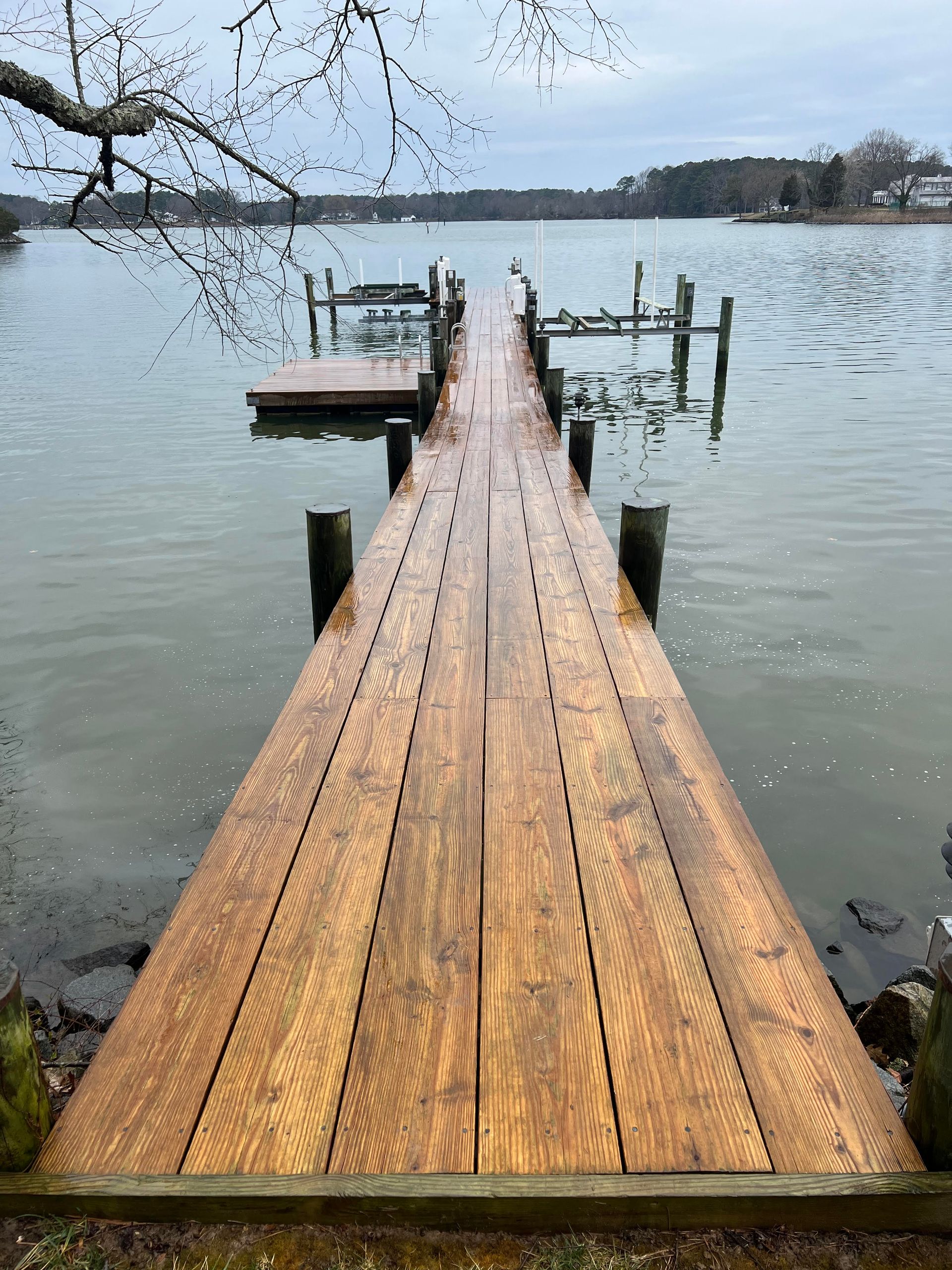 A wooden dock leading into a lake with boats in it.