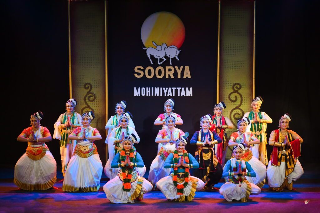 a group of people are dancing on a stage in front of a sign that says soorya .
