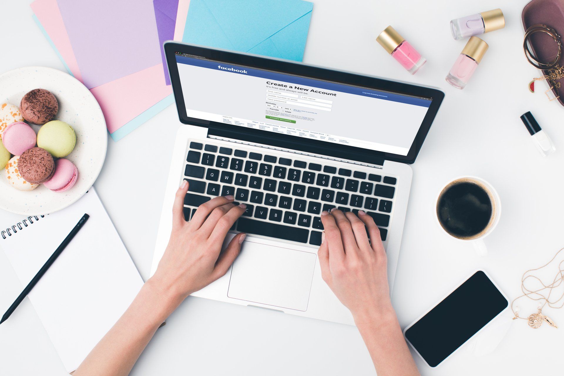 A woman is typing on a laptop next to a cup of coffee