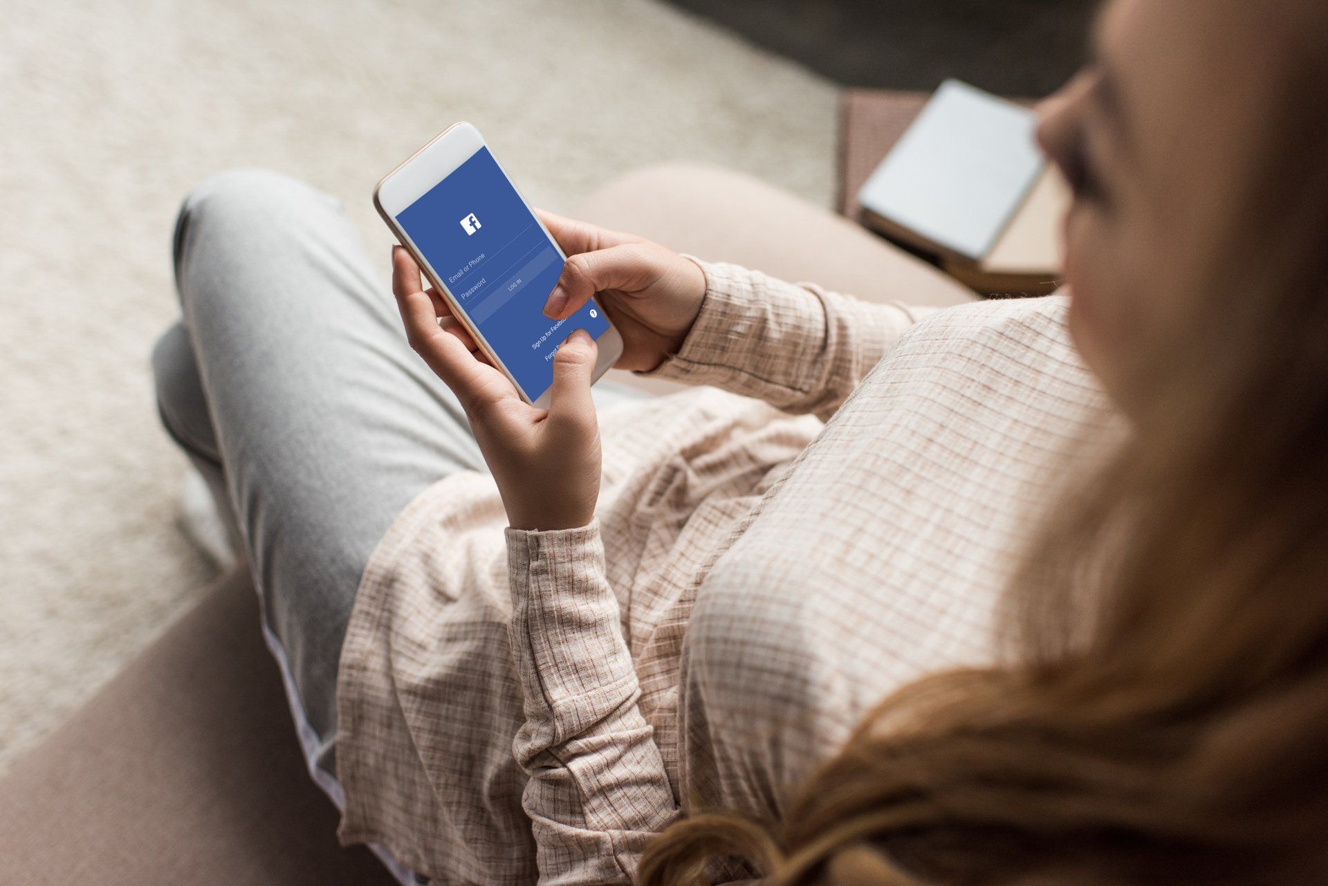 A woman is sitting on a couch looking at her phone