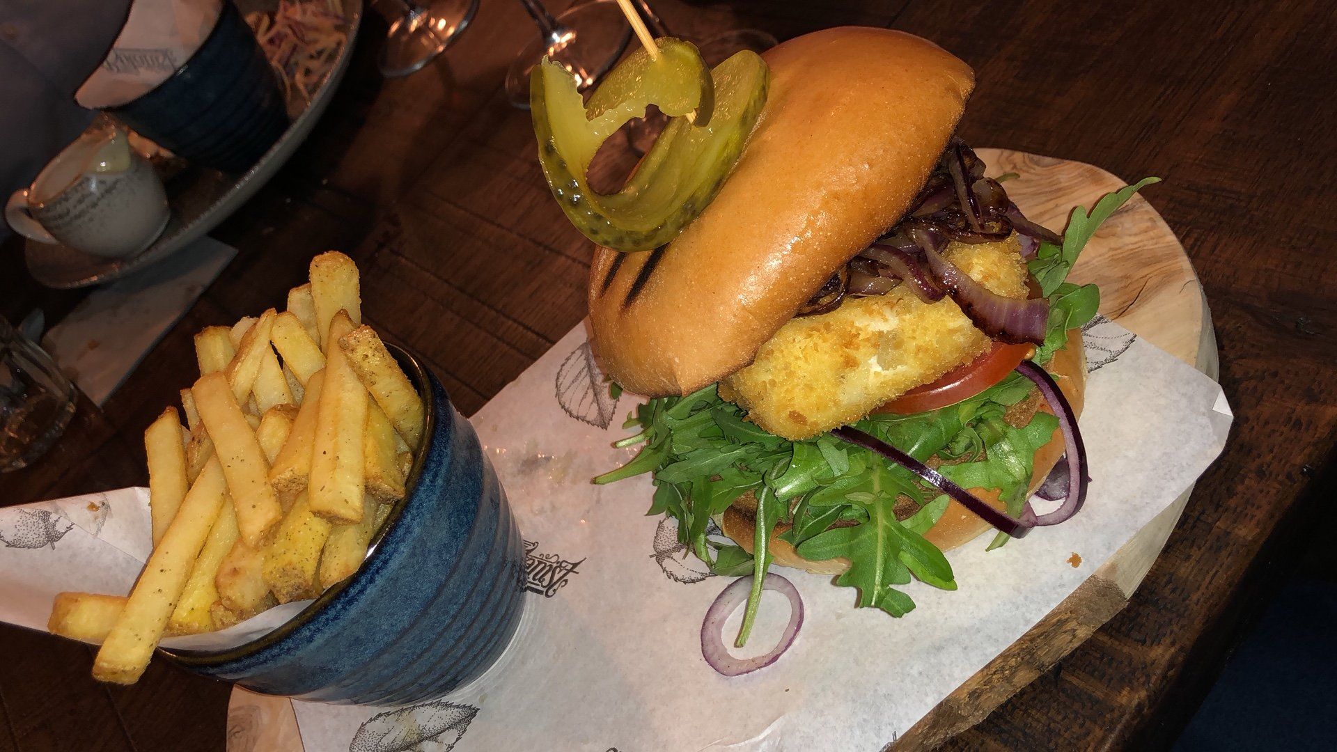 A hamburger and french fries on a wooden cutting board