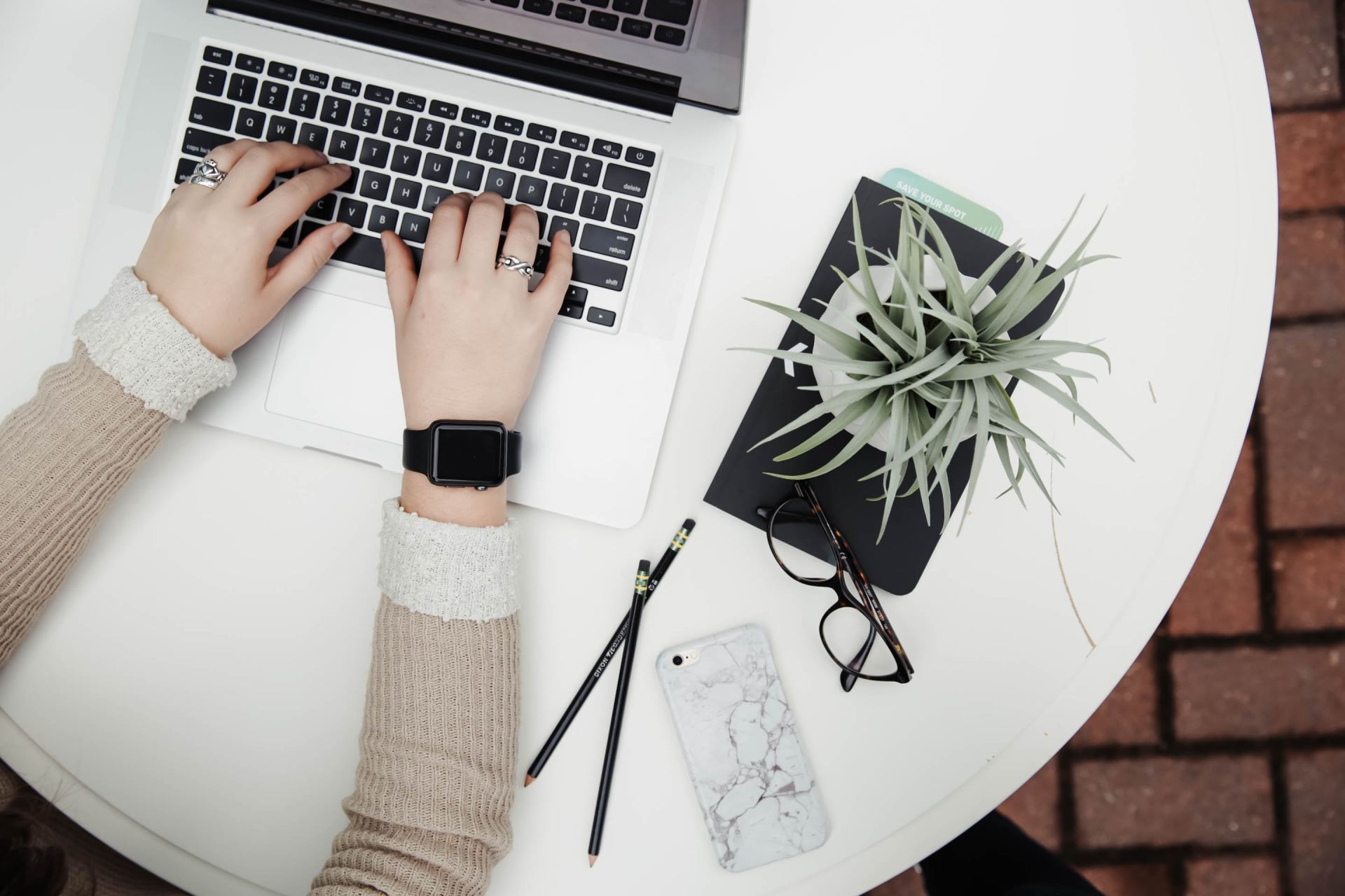 A person is typing on a laptop with a watch on their wrist