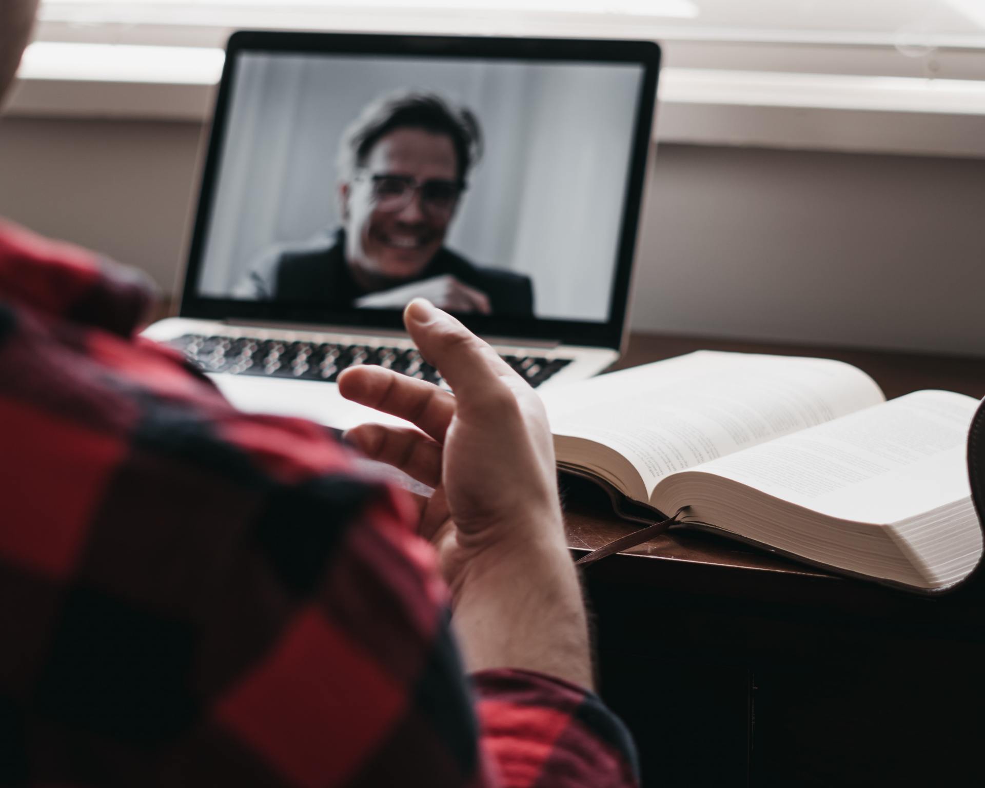 A man is sitting in front of a laptop with a picture of a man on the screen