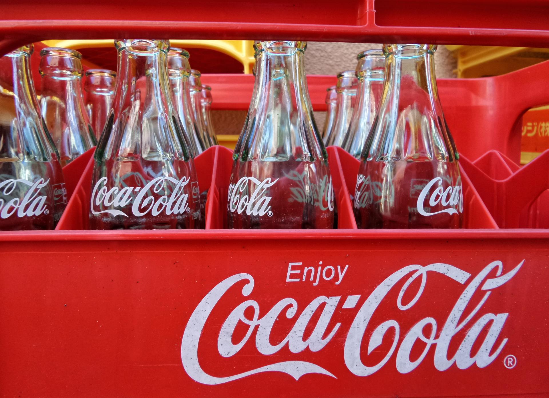 A red coca cola crate filled with empty bottles