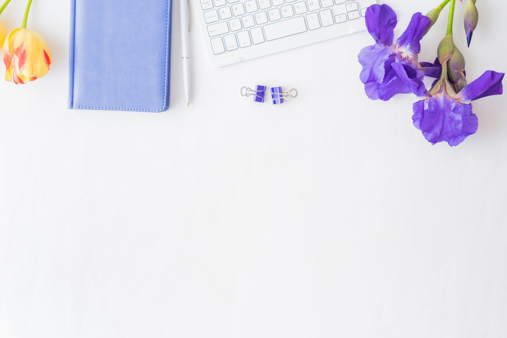 A white desk with purple flowers and a keyboard
