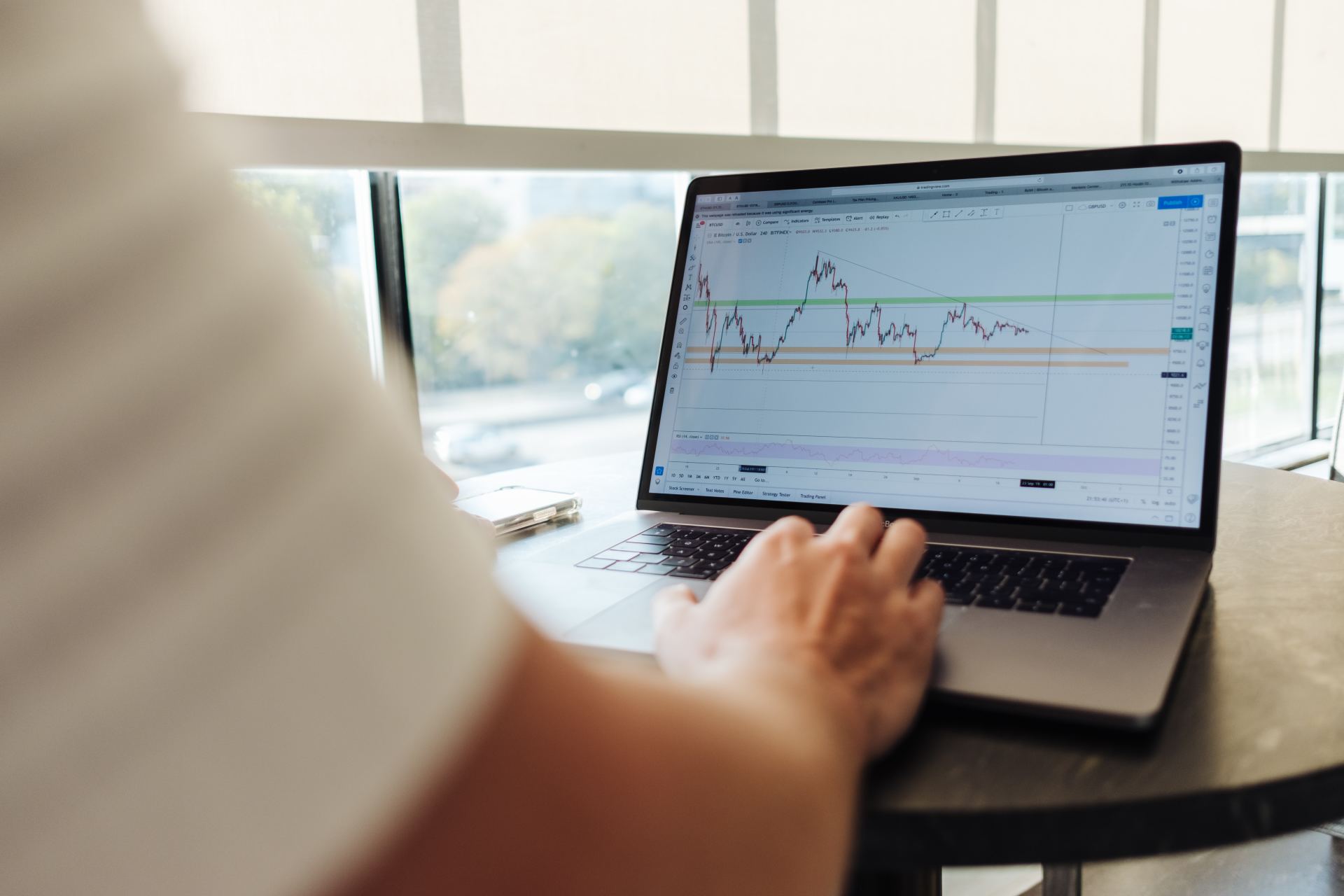 A person is typing on a laptop with a graph on the screen