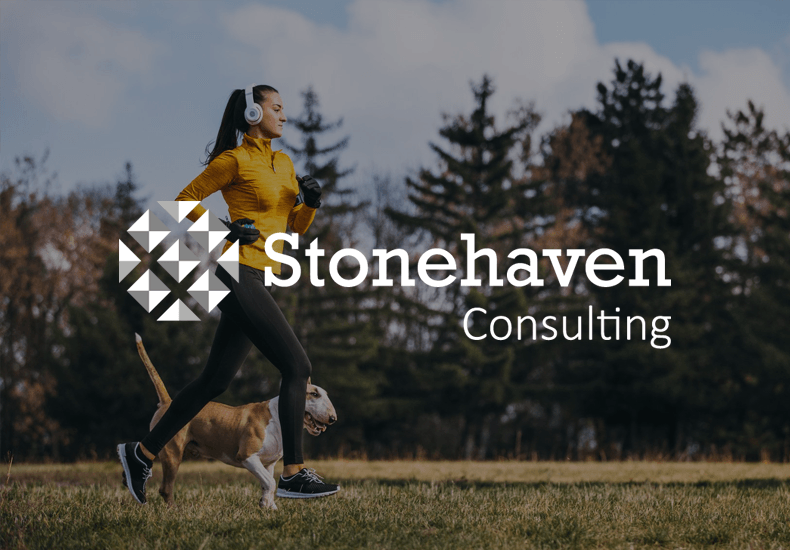 A woman wearing headphones is running with a dog in a park.