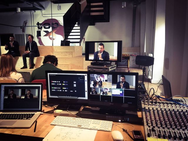 Un evento dal vivo allestito con altoparlanti, monitor e apparecchiature audio in una sede al chiuso.