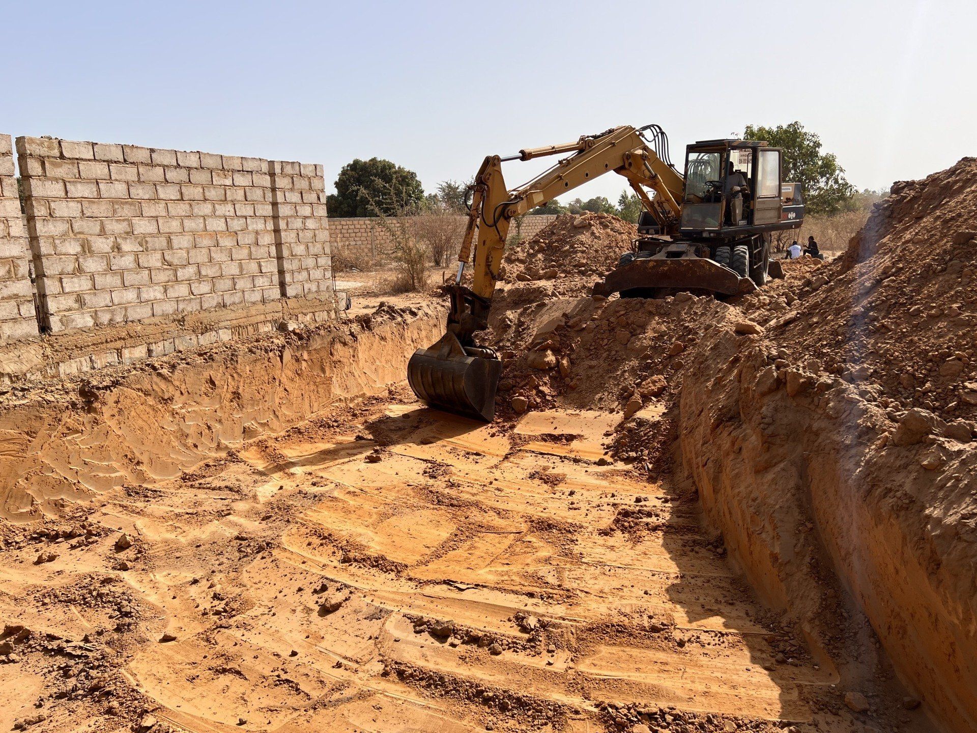 Une excavatrice jaune creuse un trou dans la terre.