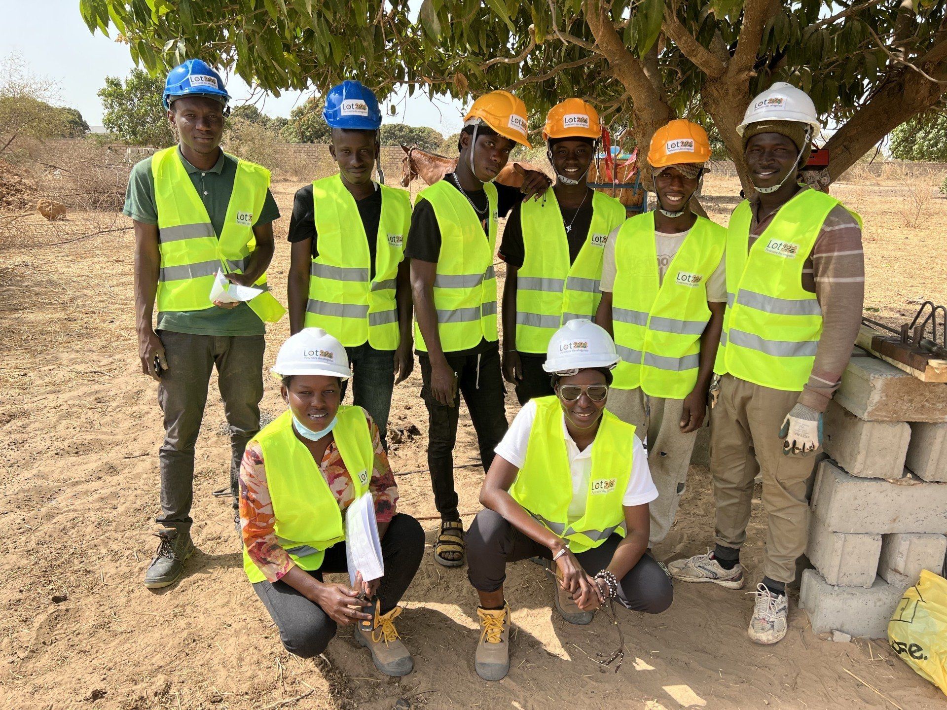Un groupe d'ouvriers du bâtiment portant des gilets jaunes et des casques de sécurité posent pour une photo.