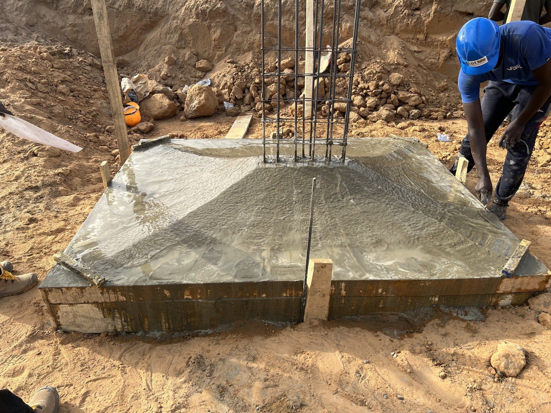 Un homme portant un casque bleu travaille sur une base en béton.
