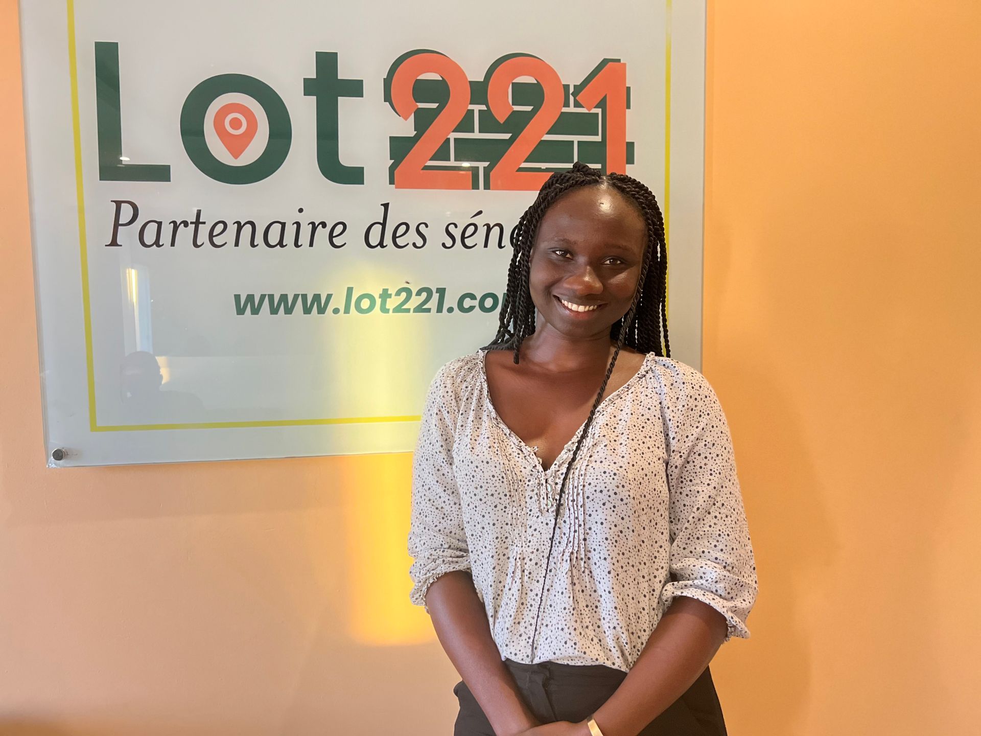 Une femme se tient devant un panneau indiquant le lot 221