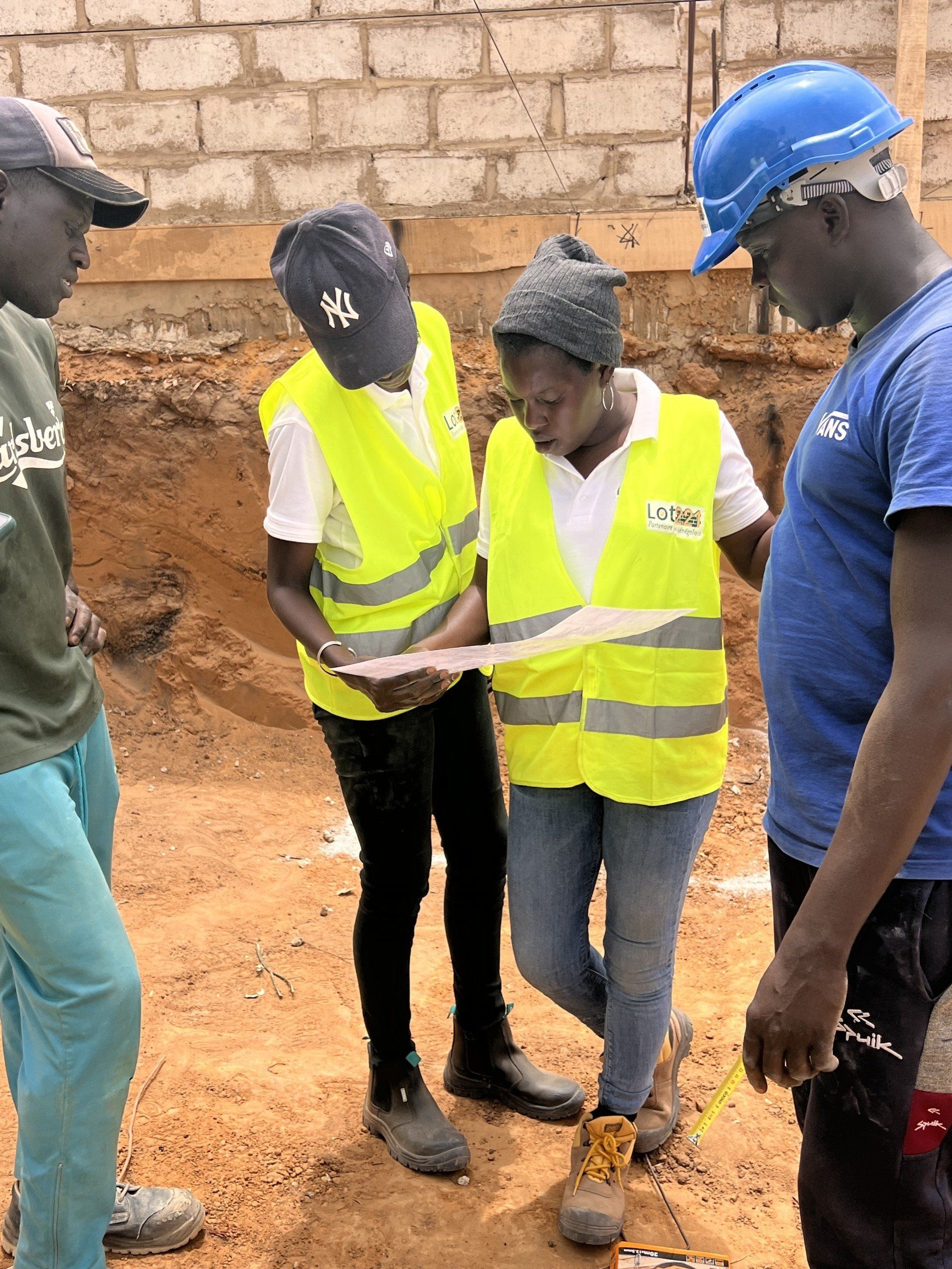 Un groupe d'ouvriers du bâtiment se tient dans la terre et regarde un morceau de papier.