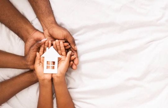 Une famille tient une maison en papier entre ses mains.